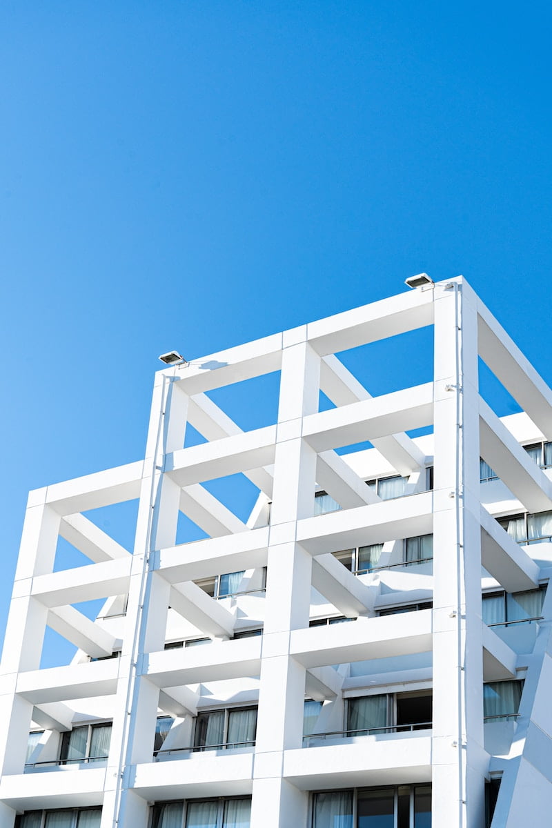 a tall white building with balconies against a blue sky